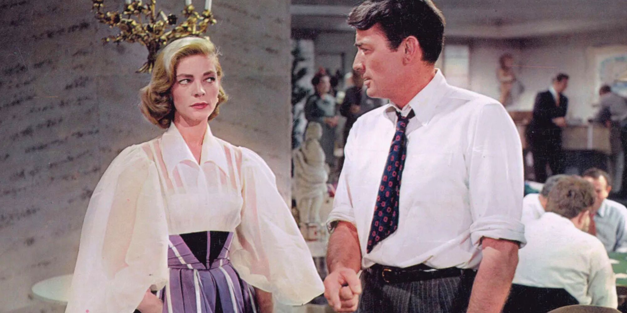 Lauren Bacall standing next to Gregory Peck both looking at each other in Designing Woman (1957).