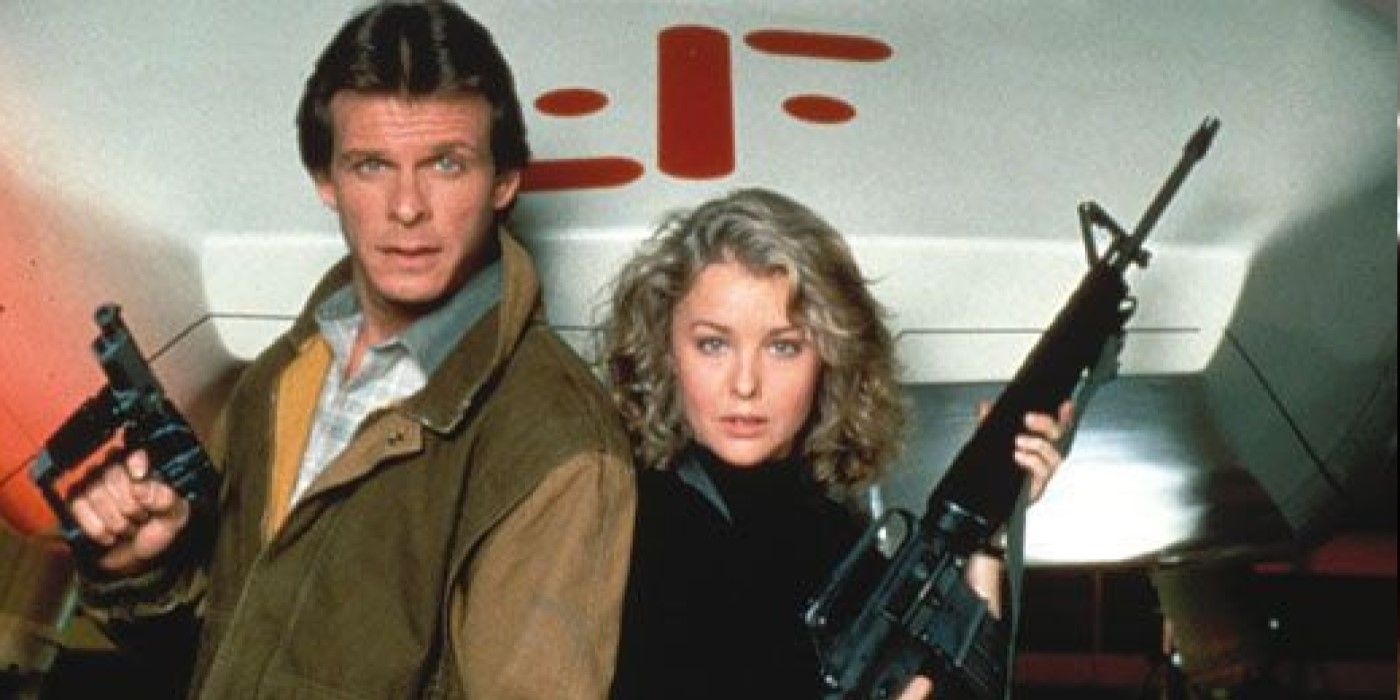 Marc Singer and Faye Grant, holding weapons in front of a space cruiser, in a promotional image for 1983's V.