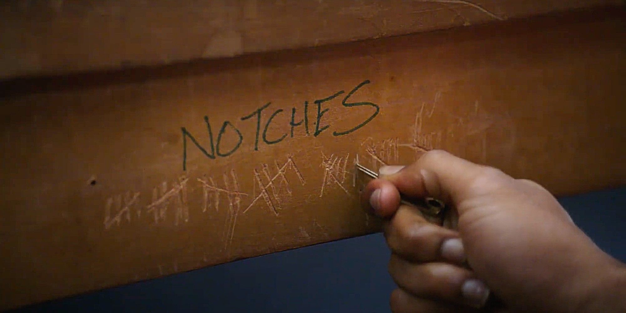 Troy Barnes' hand making a notch in the side of the table under a heading marked &ldquo;NOTCHES&rdquo; in Community Season 2