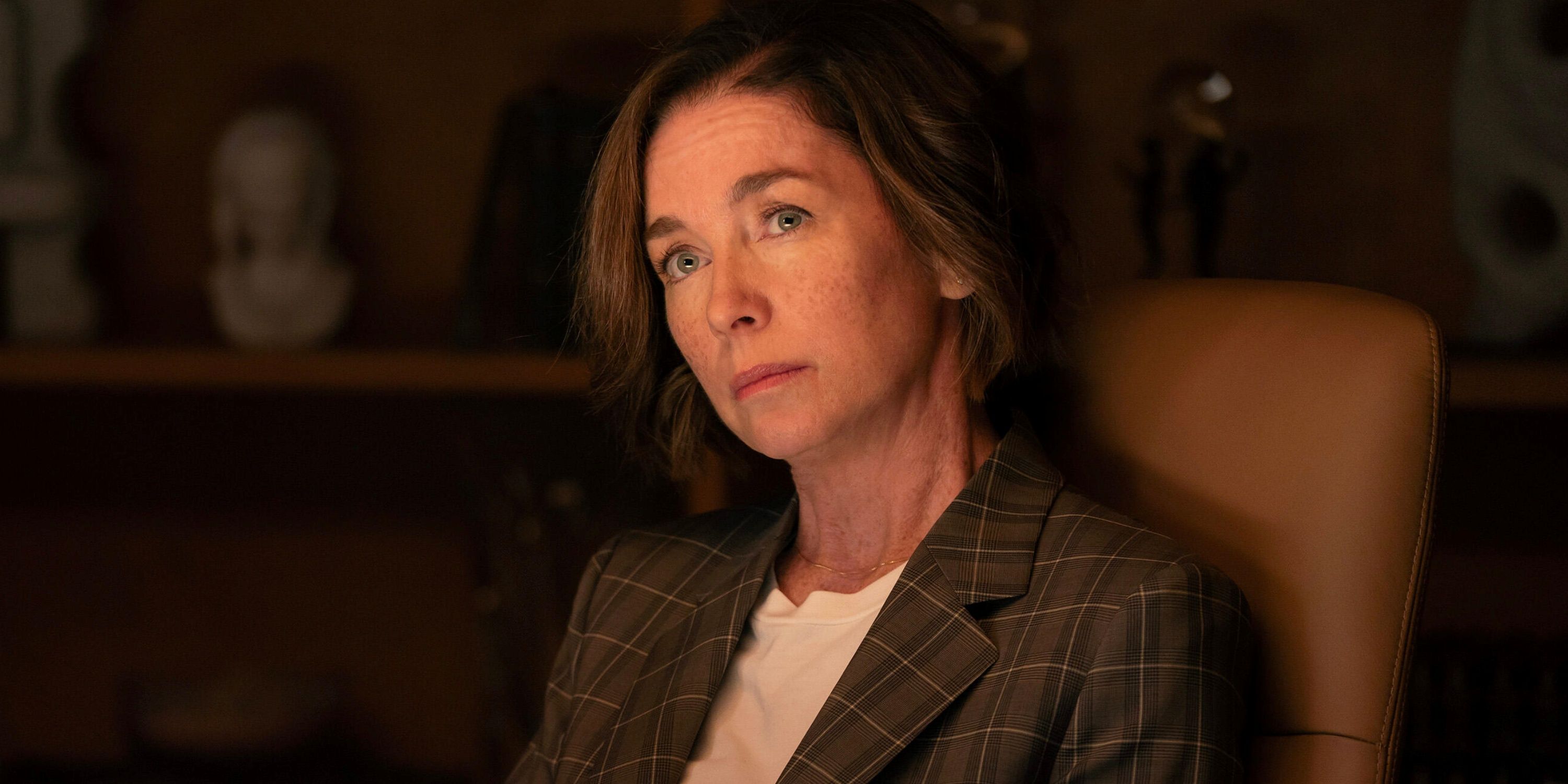 Julianne Nicholson as Sinatra sitting in a chair at a desk in her office in Paradise