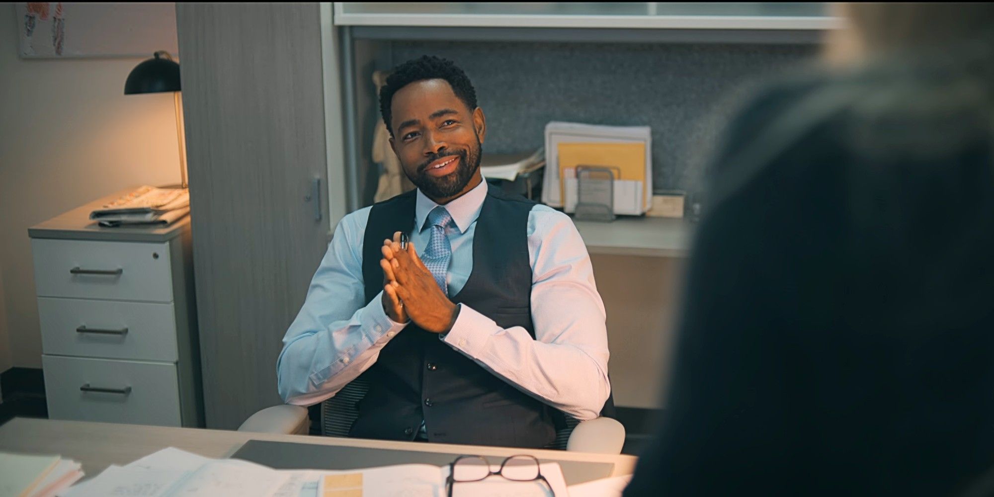 Coach Jay Brown sitting at his desk and smiling in Running Point.