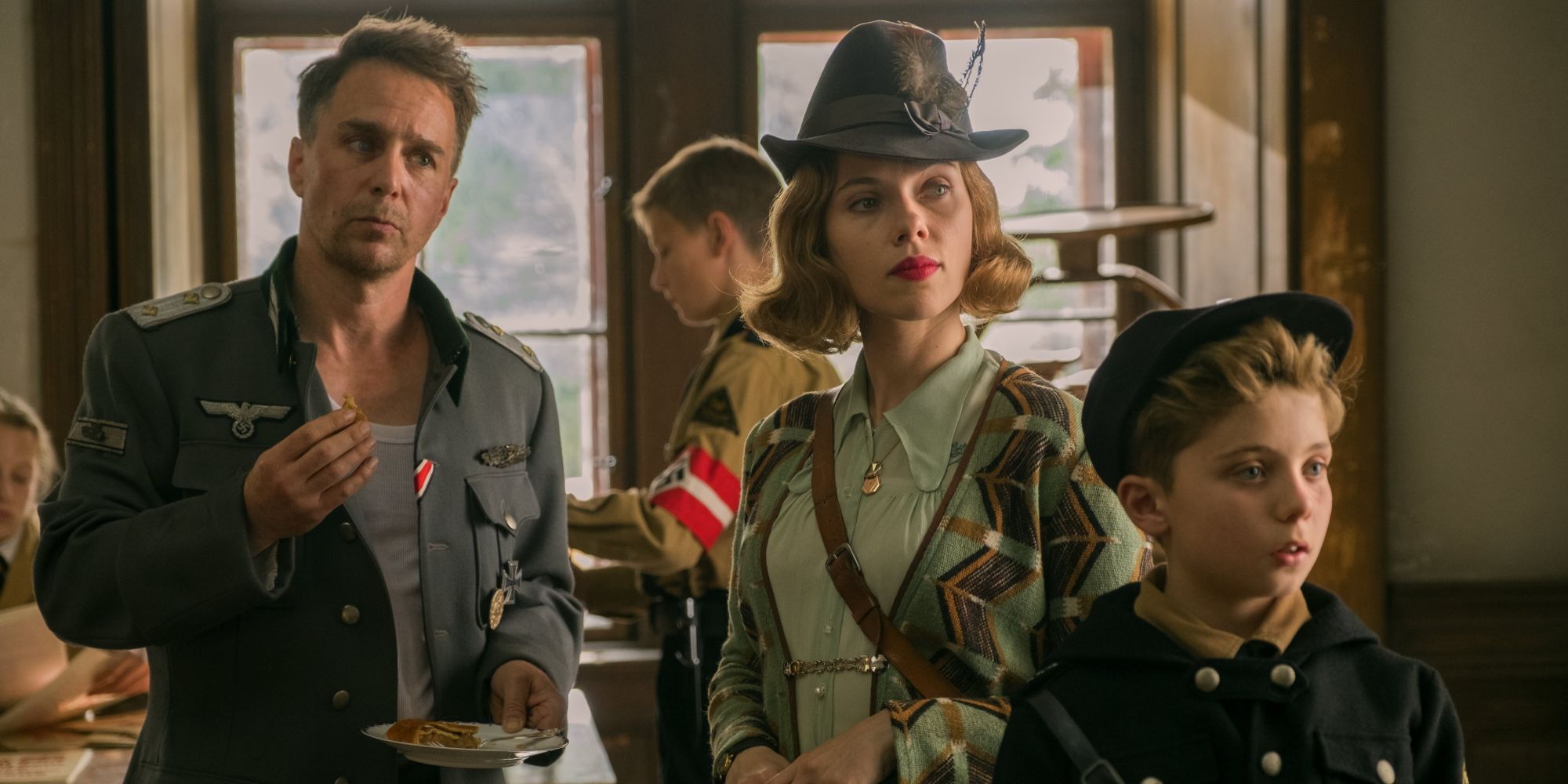 Sam Rockwell as Klenzendorf, Scarlett Johansson as Rosie, and Roman Griffin Davis as Jojo in Jojo Rabbit.