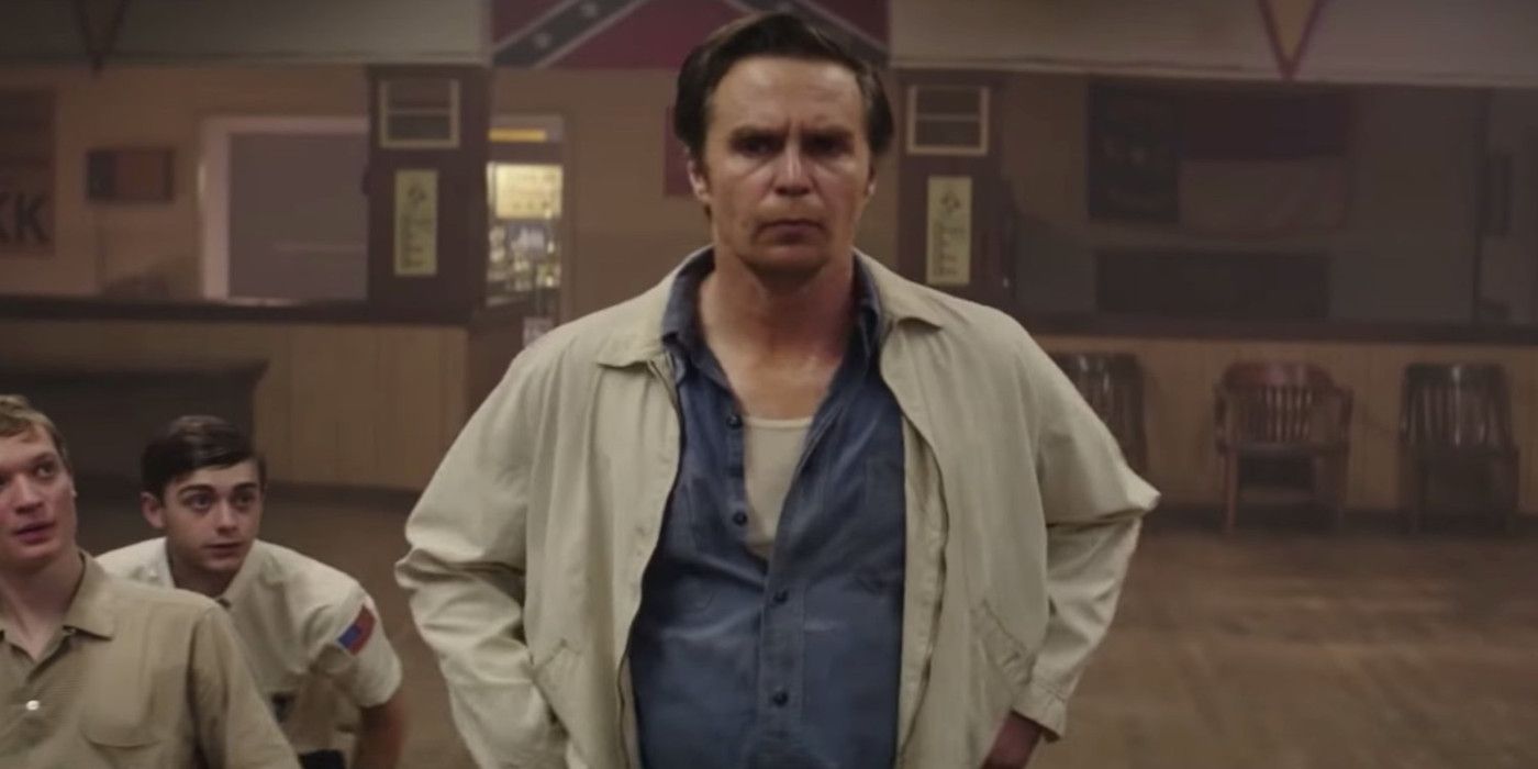 Sam Rockwell as C.P. stands with his hands on his hips with people sitting in chairs in The Best of Enemies.