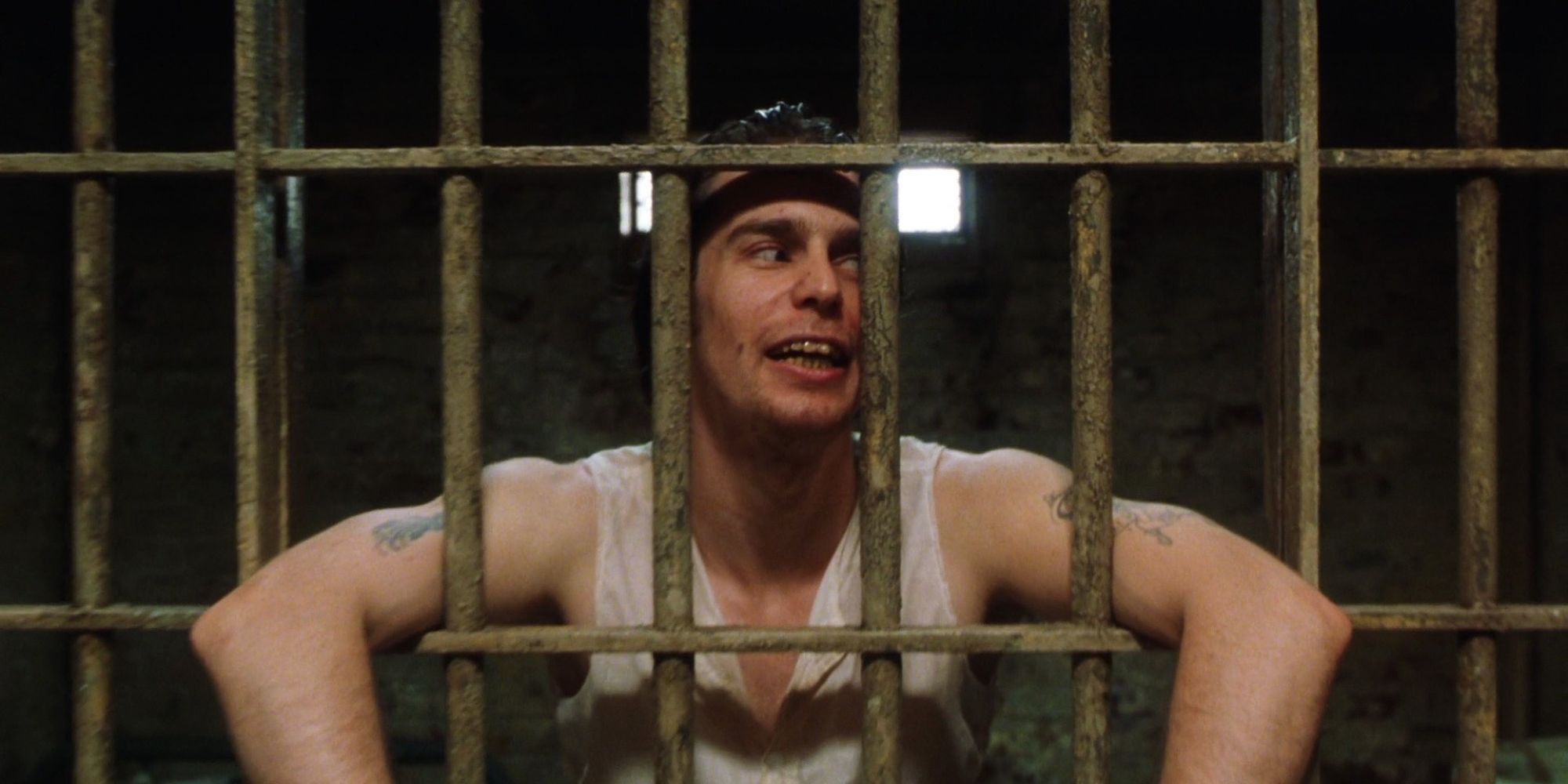Sam Rockwell as William Wharton in a prison cell with his arms hanging out and smiling in The Green Mile.