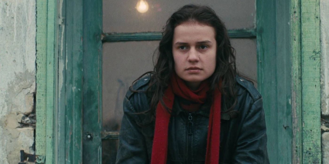 Sandrine Bonnaire as Mona Bergeron in a leather jacket and red scarf in Vagabond