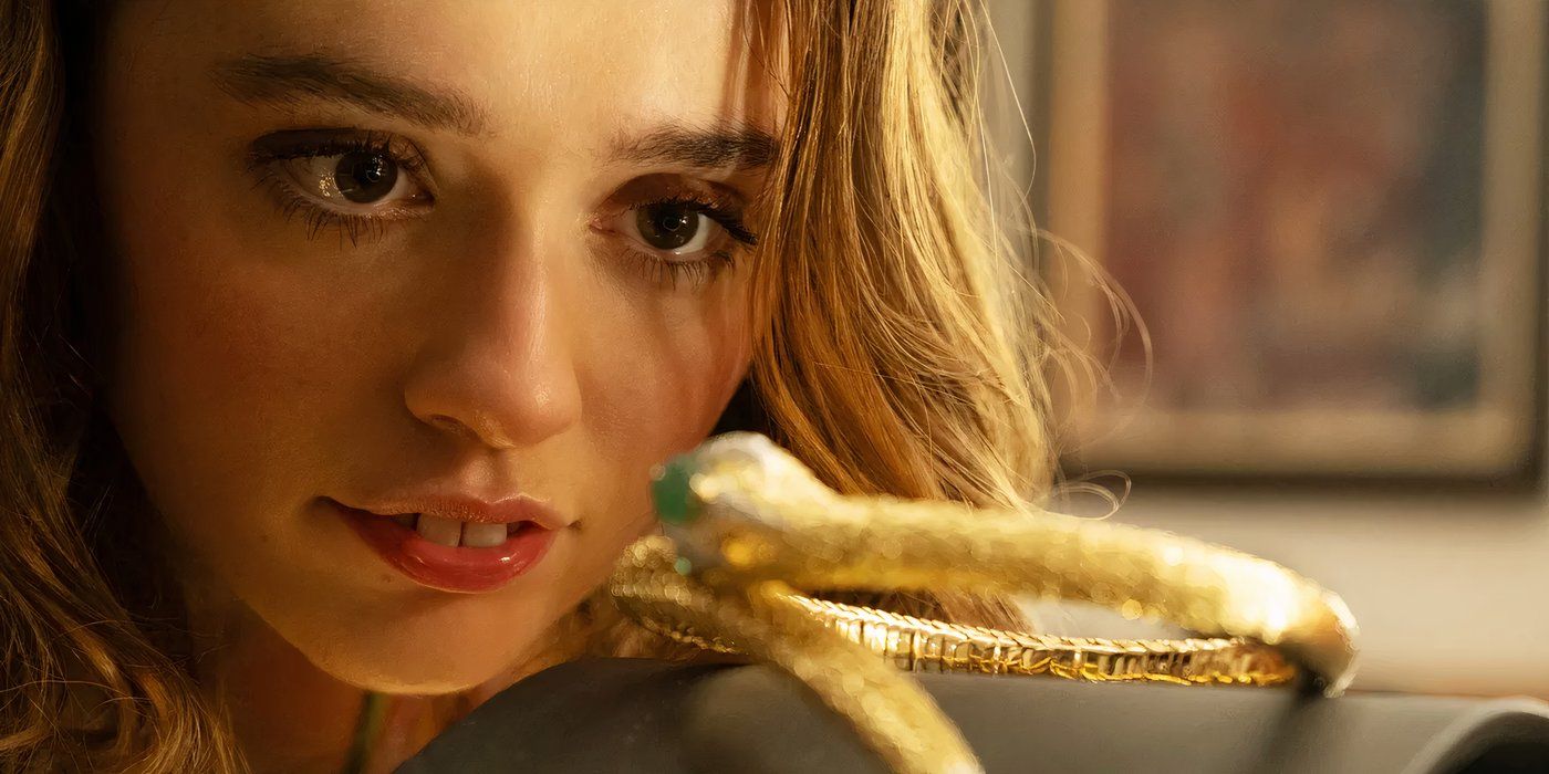 Aimee Lou Wood as Chelsea in White Lotus looks at a piece of jewelry in episode 2, season 3.