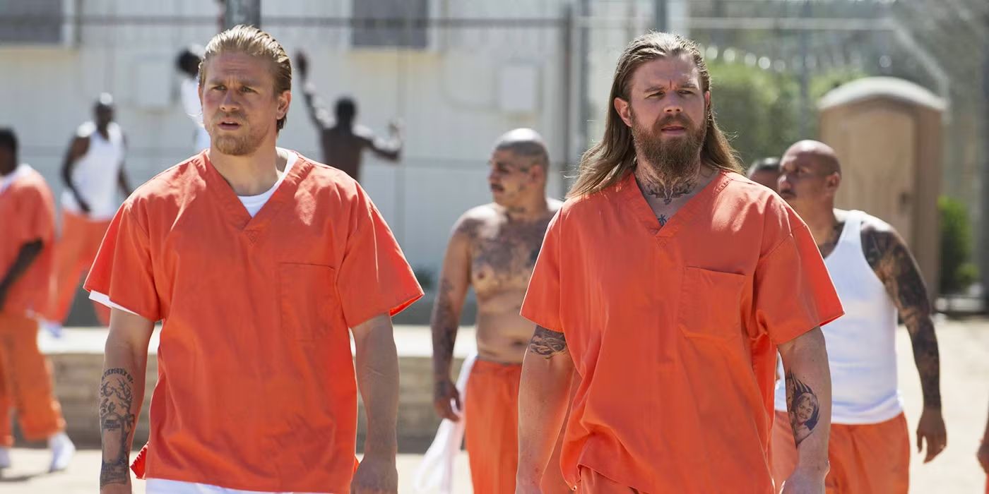 Jax and Opie in prison jumpsuits walking through the prison yard in Sons of Anarchy.