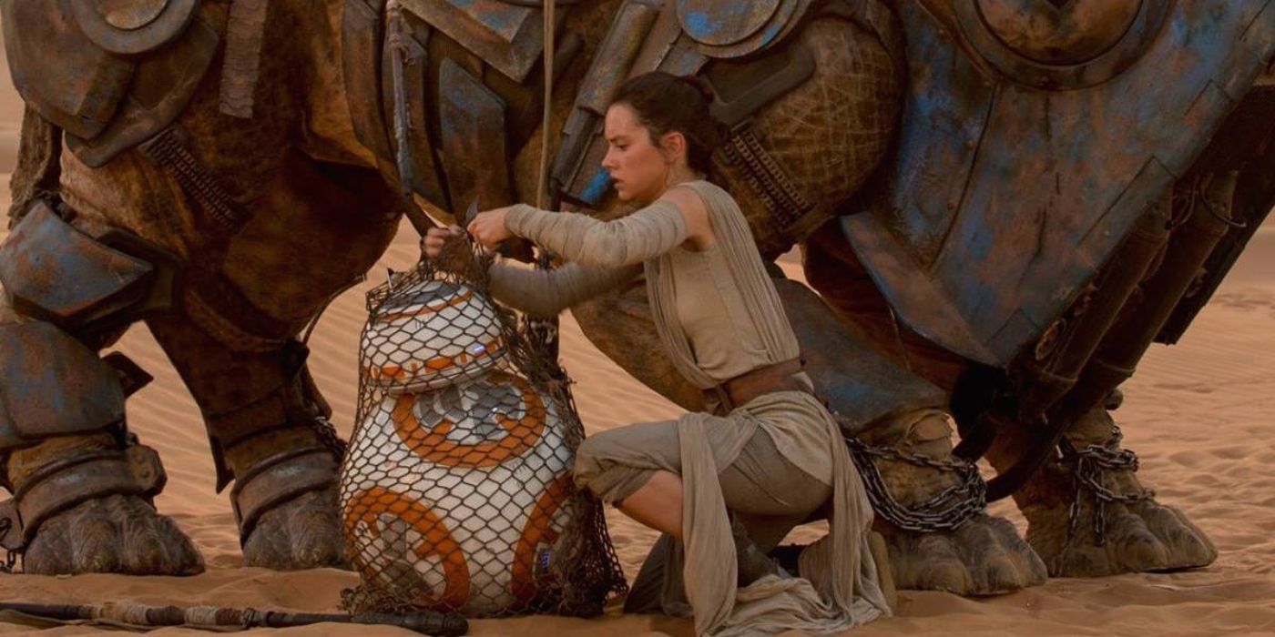 Daisy Ridley as Rey helps BB8 who is in a net in front of a large animal in Star Wars: The Force Awakens.