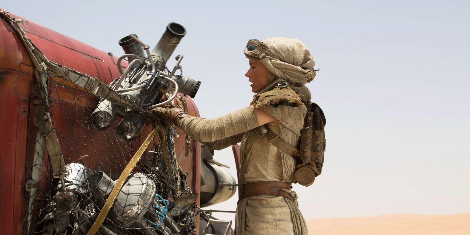 Daisy Ridley as Rey loads things into a net carried by a large animal in Star Wars: The Force Awakens.