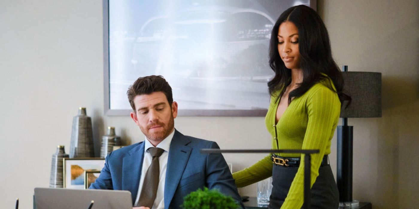 Lex Scott Davis as Erica standing next to Bryan Greenberg as Rick sitting at his desk in Suits: LA