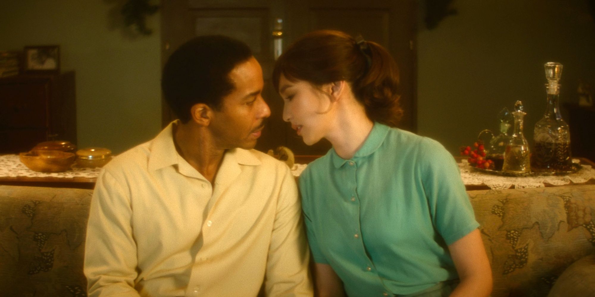 André Holland as Paul and Gemma Chan as Edna leaning in for a kiss on the couch in The Actor