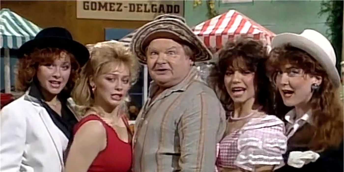 Benny Hill making a goofy face, surrounded by four other women on The Benny Hill Show.