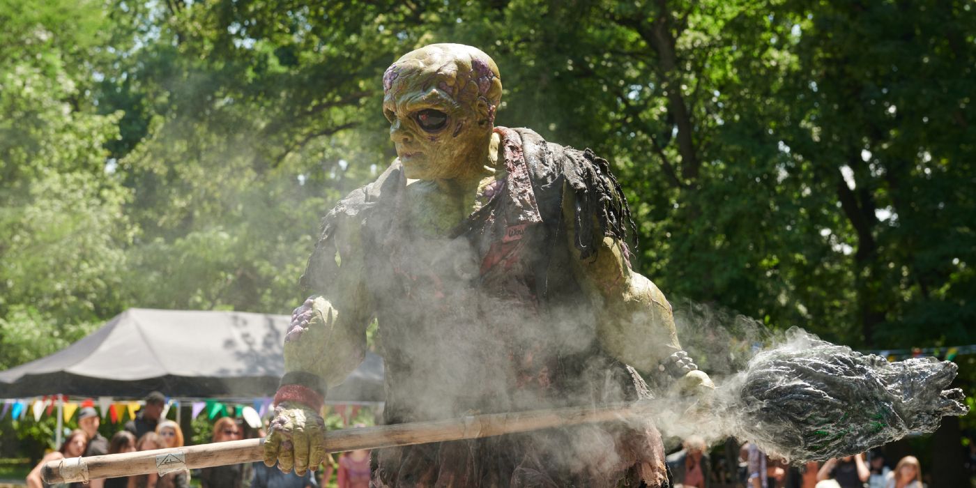 Peter Dinklage's Toxie holding his smoking mop while people watch in The Toxic Avenger (2023)