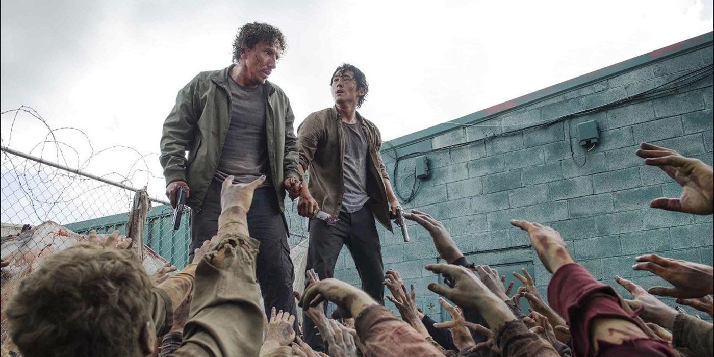 Nicholas and Glenn atop a dumpster surrounded by walkers reaching up for them on The Walking Dead.