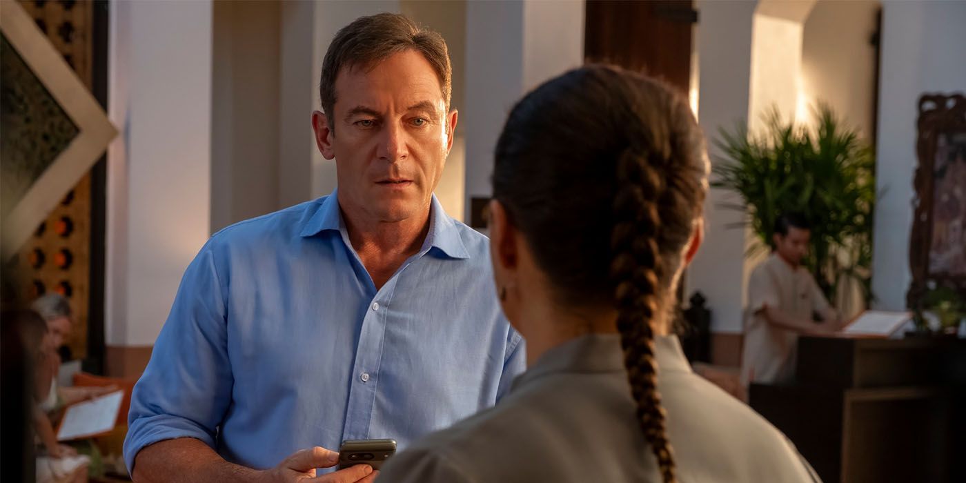 Jason Isaacs talks to a person with braided hair in The White Lotus. 
