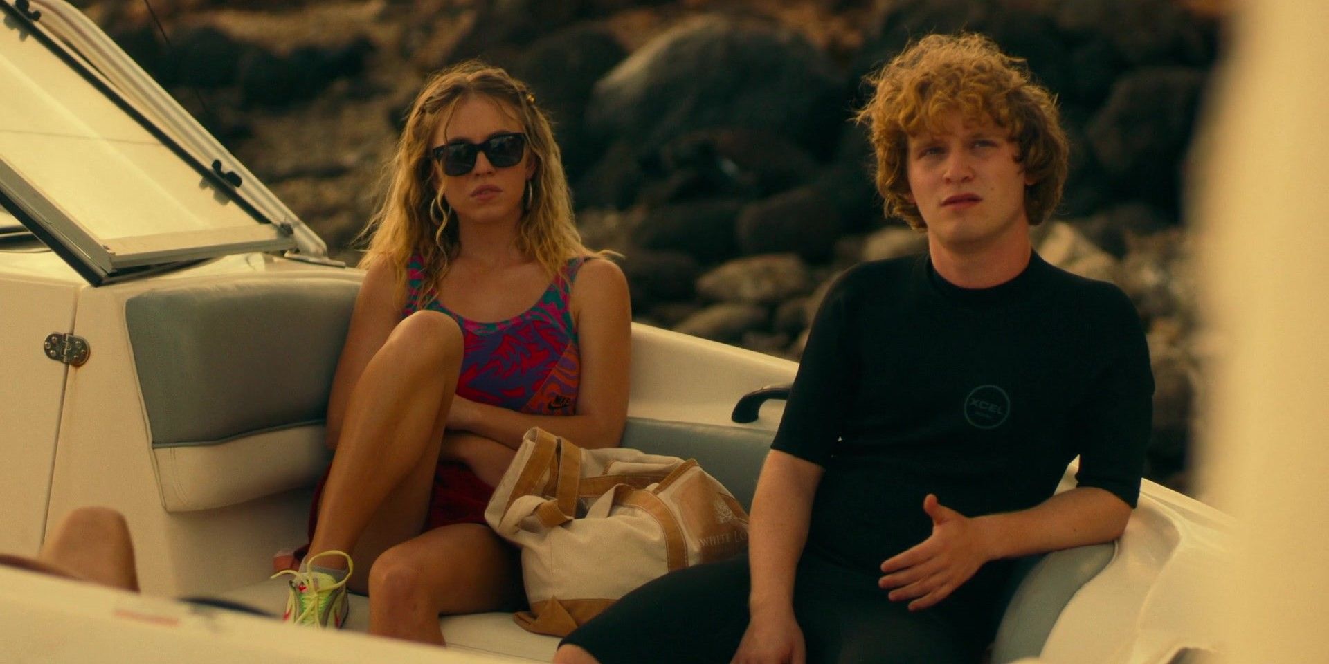 Two young people sit on a boat and look bored in The White Lotus.