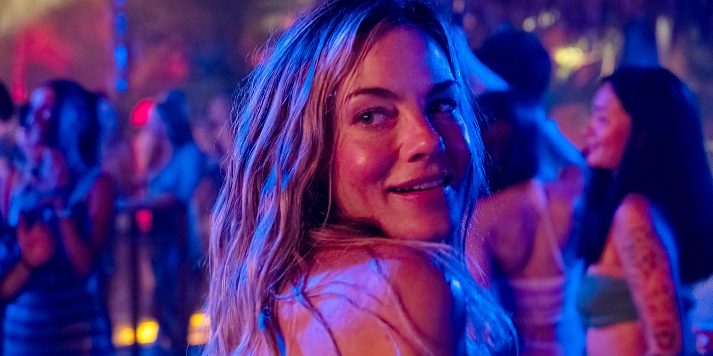 Michelle Monaghan souriant et regardant par-dessus son épaule dans un club dans le Lotus blanc