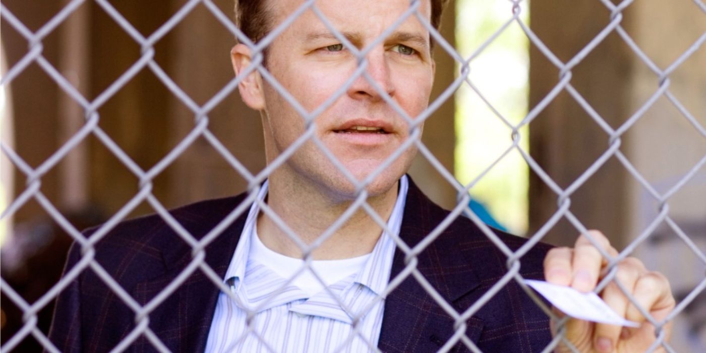 A man passes a small piece of paper through a fence in The Wire.
