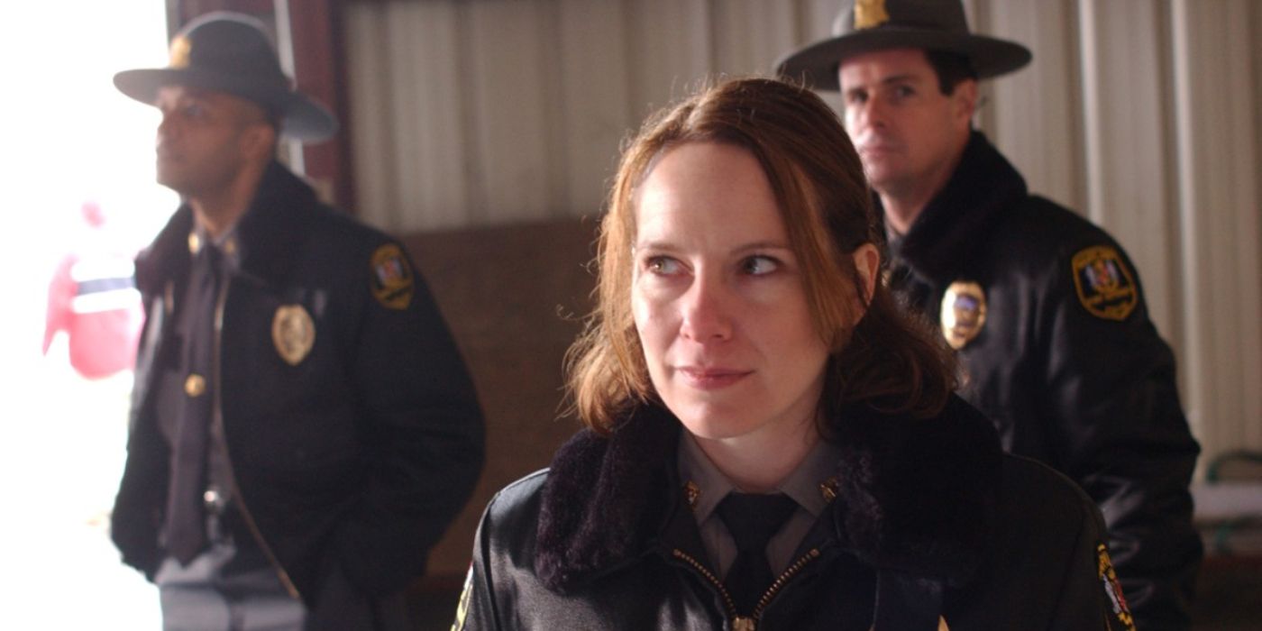 Three police officers, one woman and two men, stand in a room and look about in The Wire.