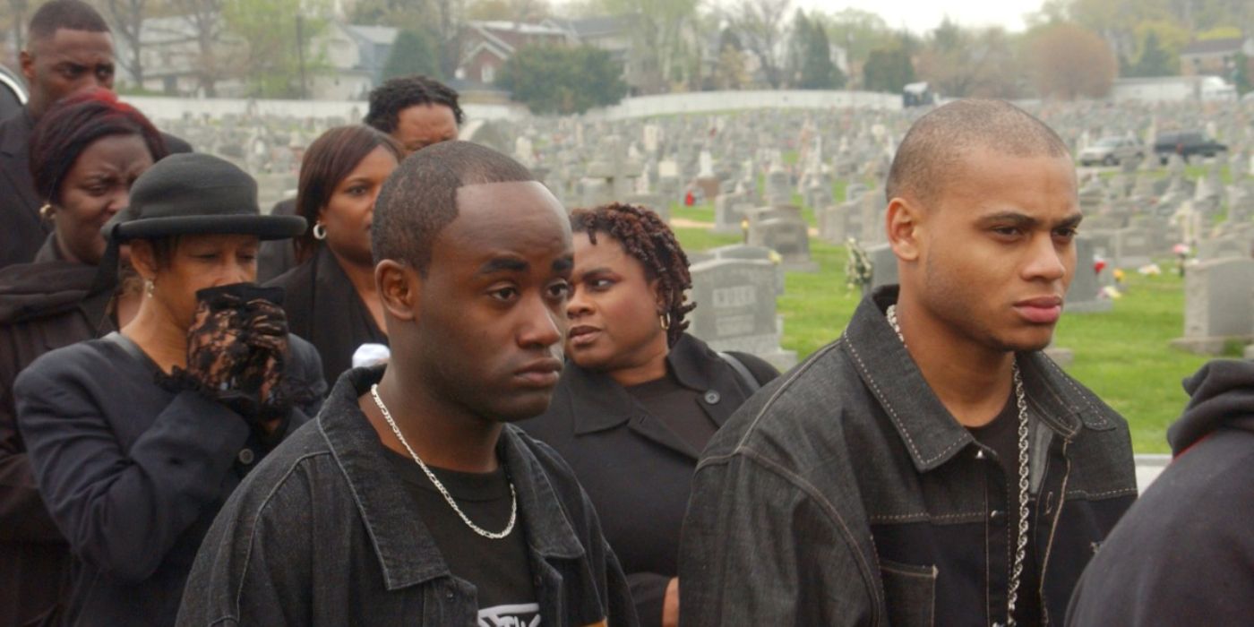 A funeral procession walks through a graveyard looking somber in The Wire.