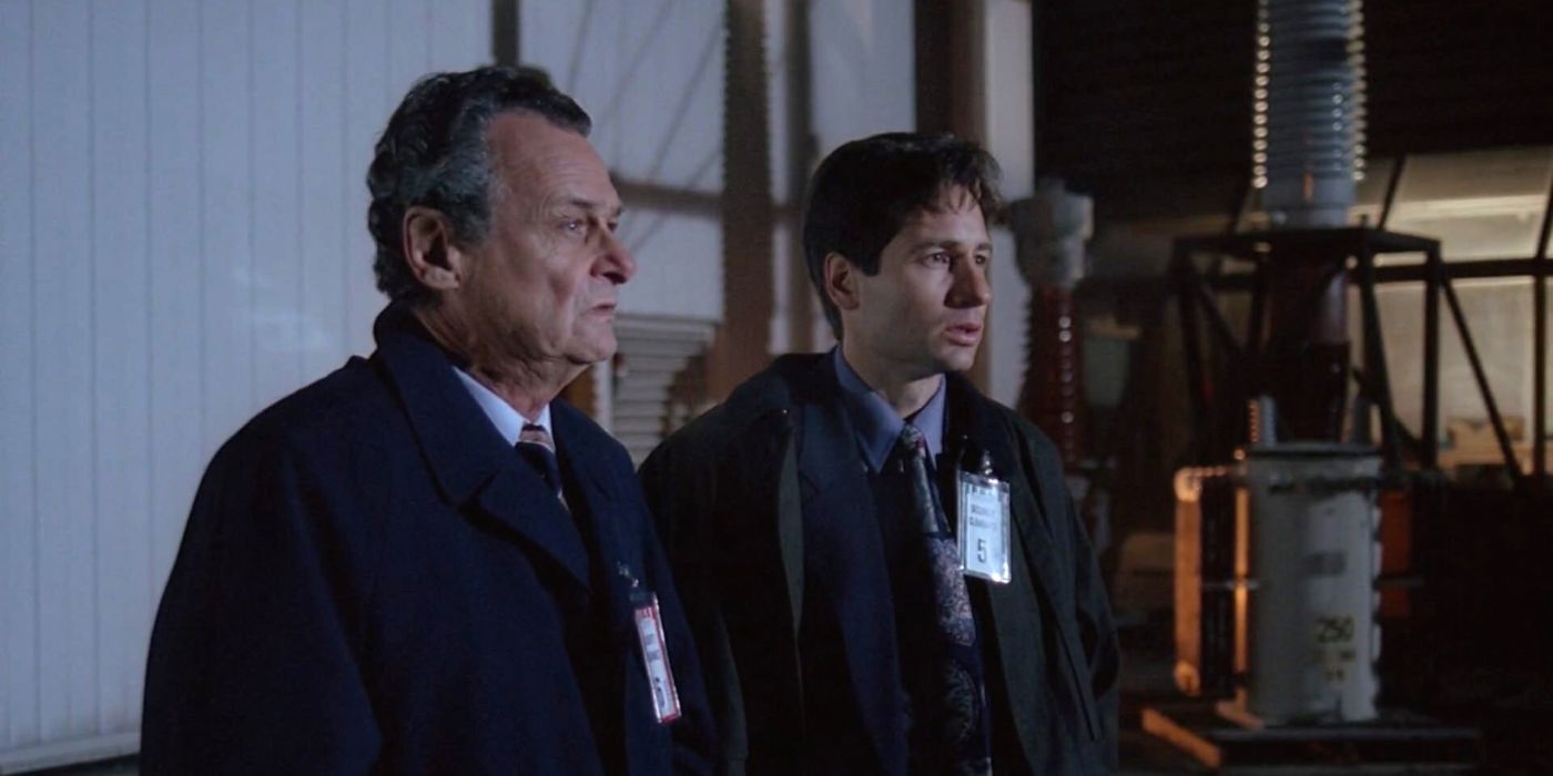 Two FBI agents stand outside at night with badges on their lapels in The X-Files.