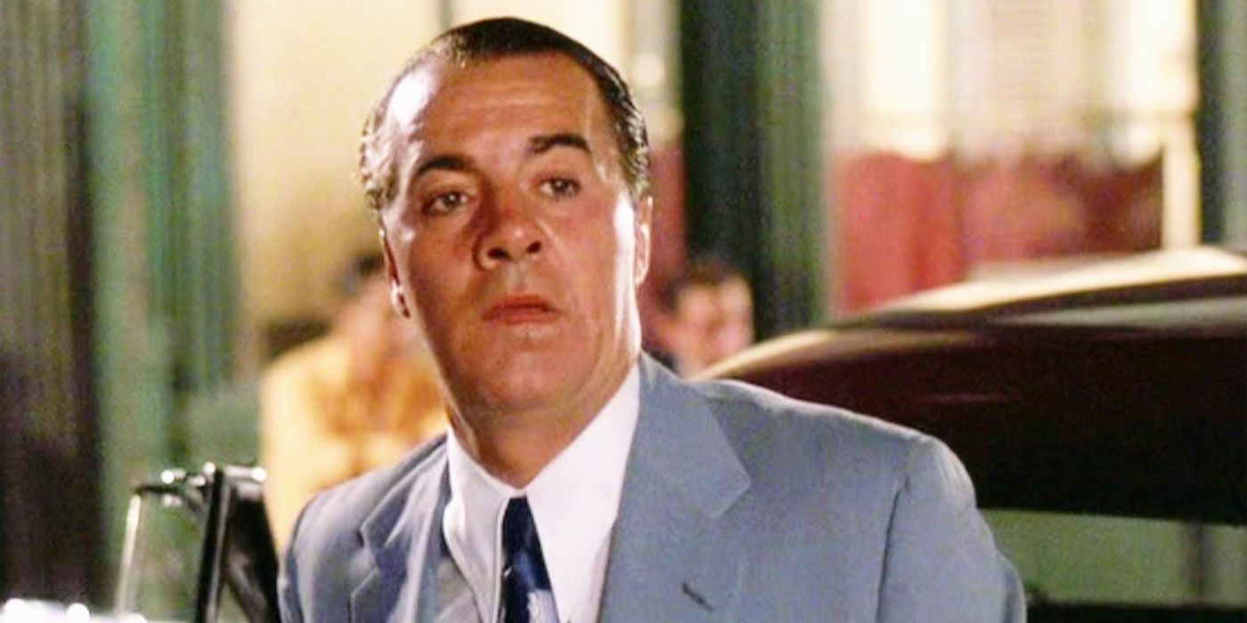 Tony Sirico in a business suit and tie looking at something off-camera in Goodfellas, 1990.