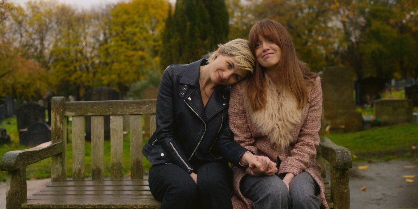 Jodie Whittaker leaning her head on another woman's shoulder on a park bench in Toxic Town