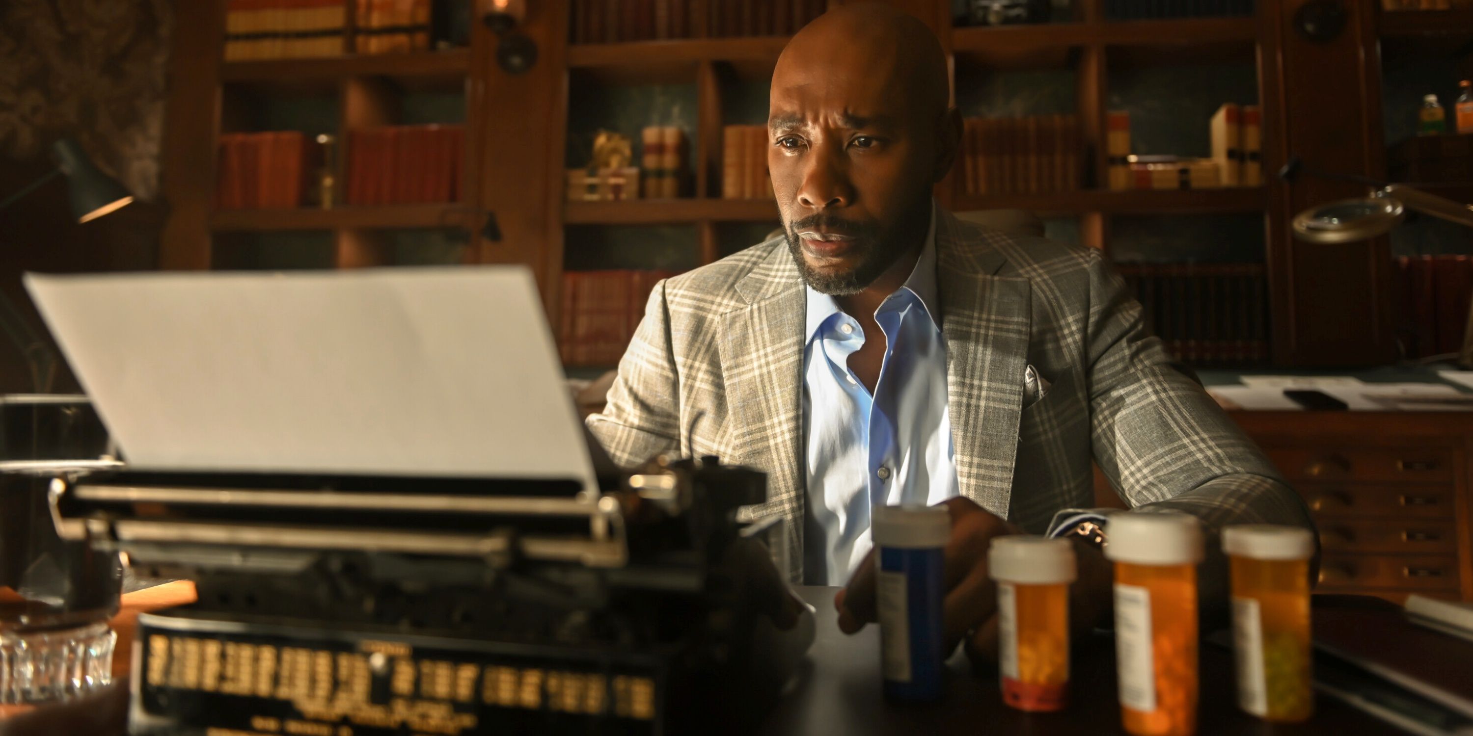 Morris Chestnut as Dr. John Watson sitting at his office desk while using a typewriter in CBS' Watson