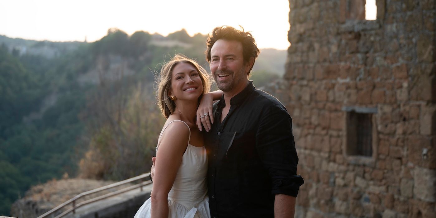 Stassi Schroeder and husband Beau Clark smiling in front of an Italian castle on 'Vanderpump Villa' Season 2