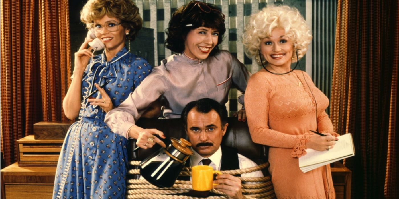 The cast of &lsquo;9 to 5&rsquo; smile around their boss who is tied up in an office chair in a promo photo.