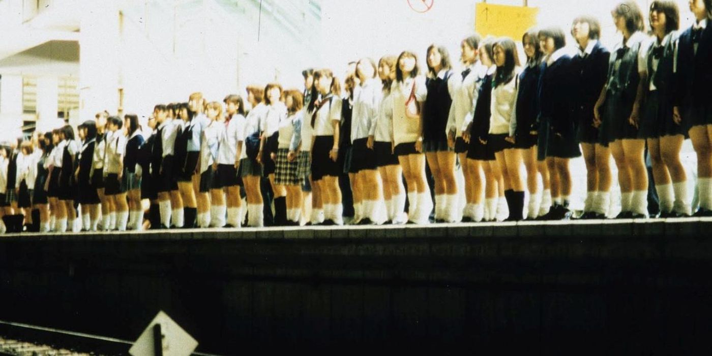 A row of schoolgirls standing at the edge of a train terminal in Sion Sono&rsquo;s Suicide Club