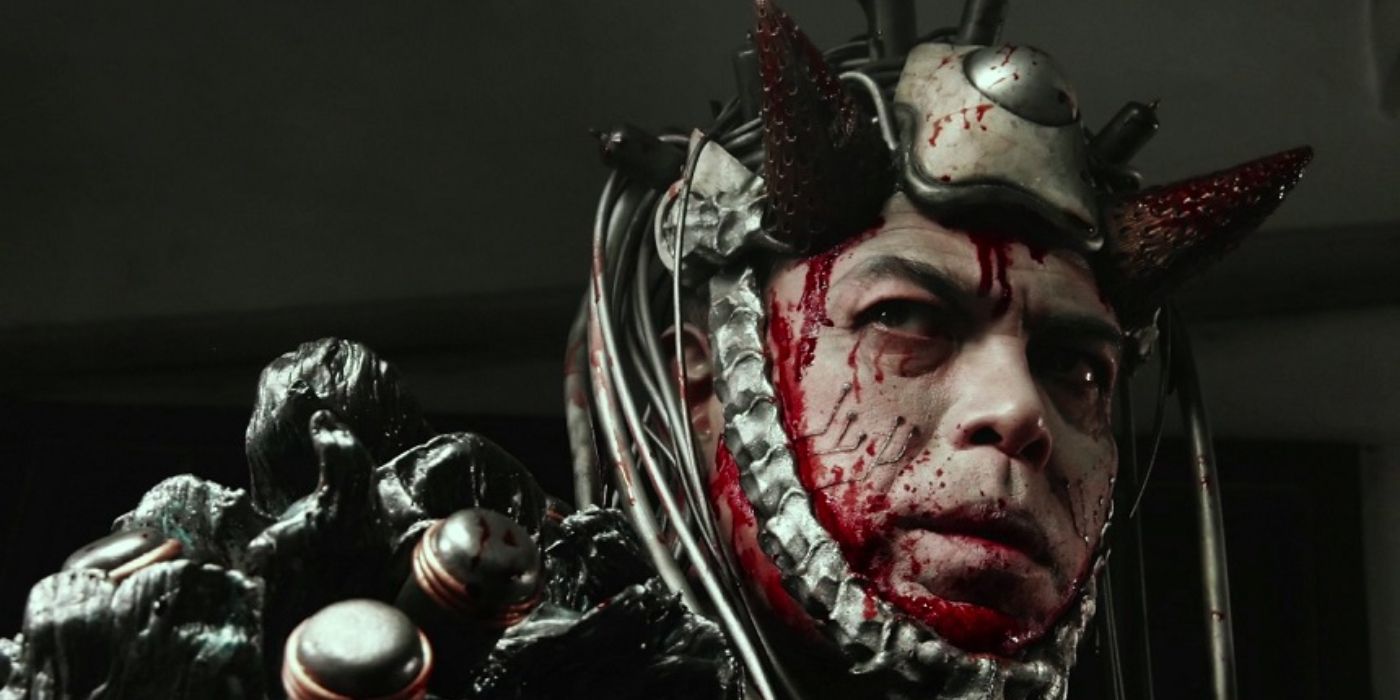 A transformed humanoid alien wearing a metal costume with blood around the edges and looking menacing in Meatball Machine Kodoku