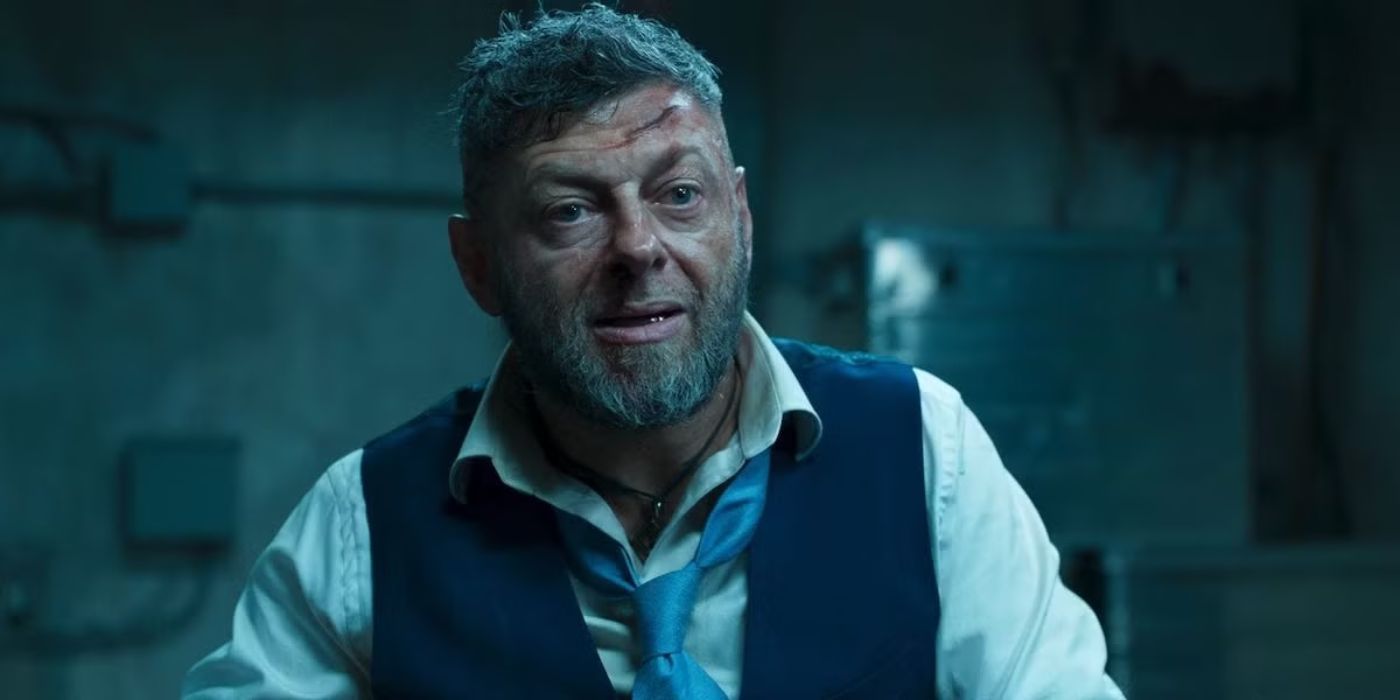 Andy Serkis as Ulysses Klaue with a cut on his forehead looks at someone off-camera in Black Panther.
