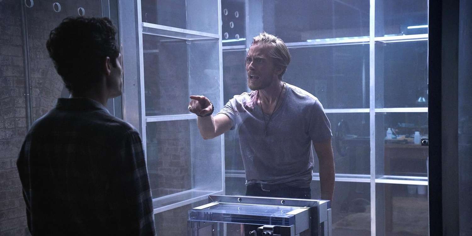 Benji (Lou Taylor Pucci) inside a glass cage pointing angrily at Joe Goldberg (Penn Badgley) in You Season 1
