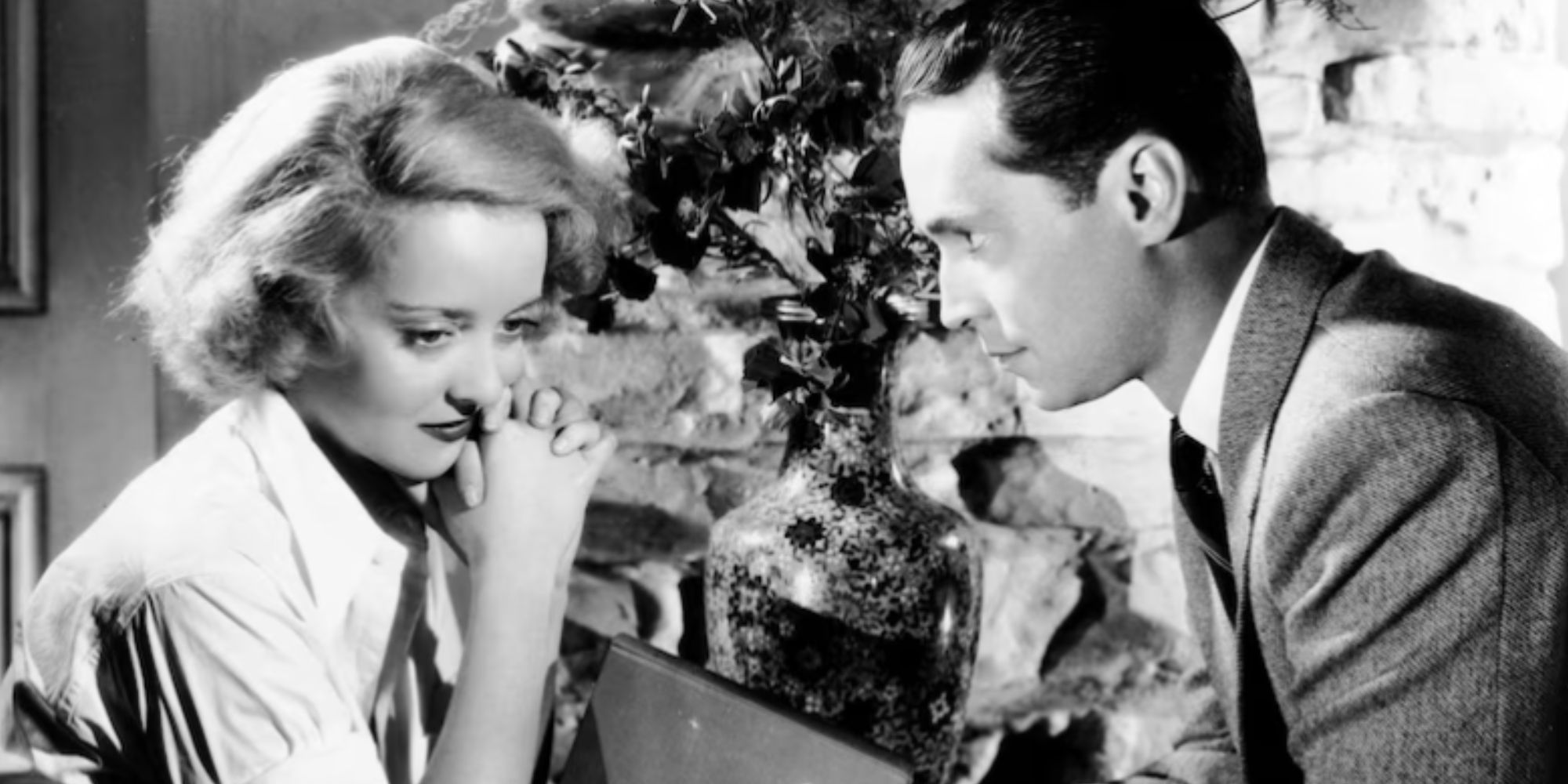 Bette Davis sitting in front of Franchot Tone in Dangerous (1935)