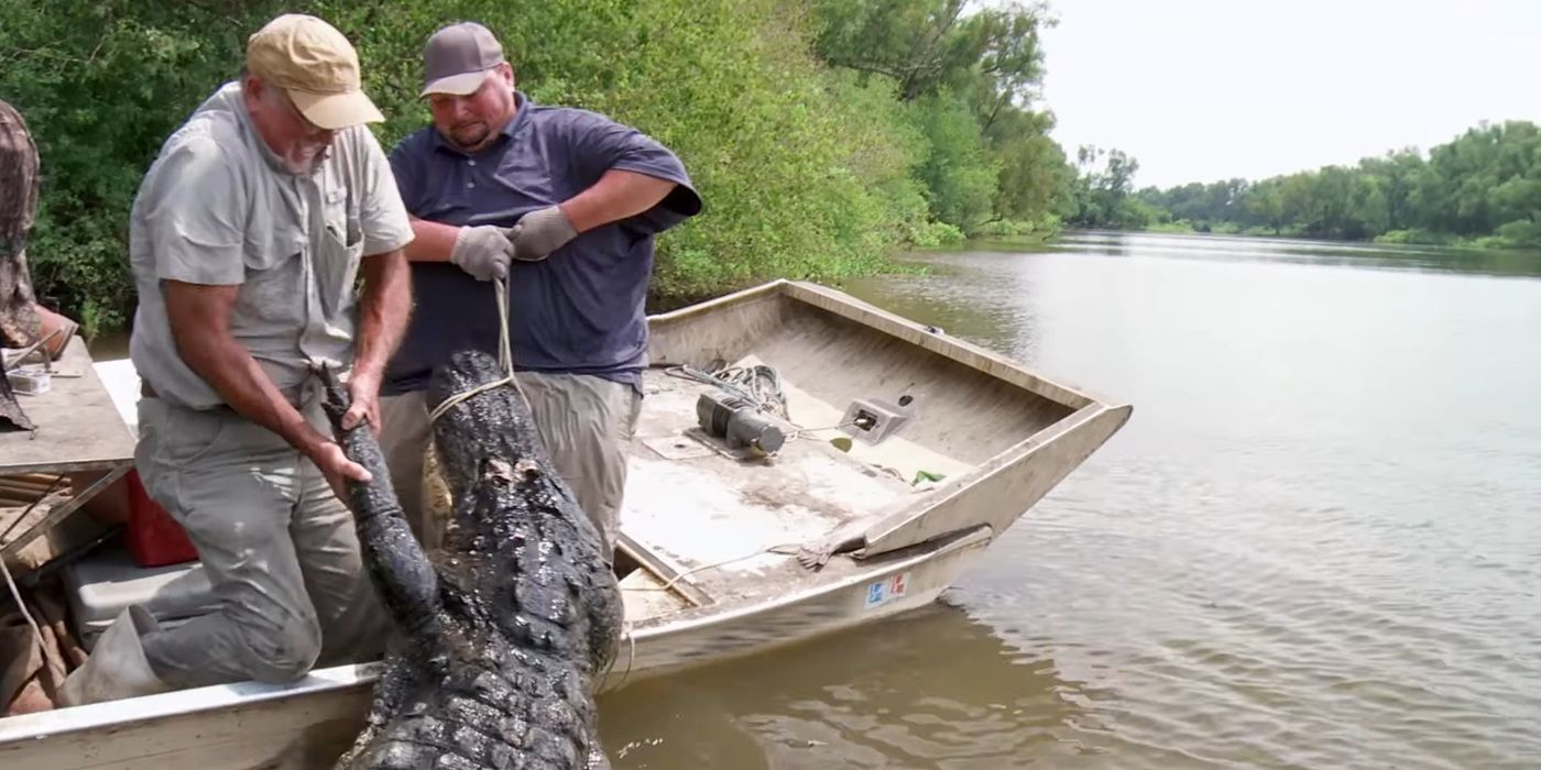 Big T and Daniel from Swamp People hauling a massive alligator onto their small boat by themselves.