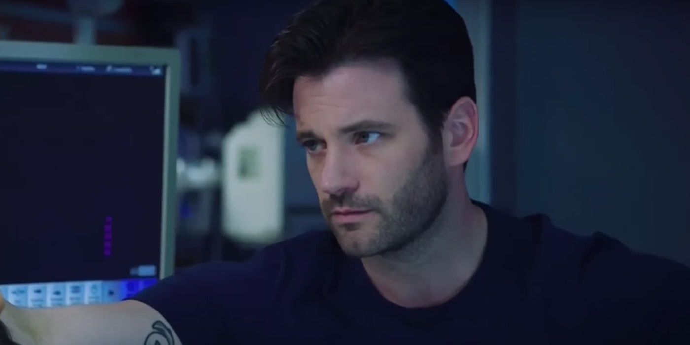 Colin Donnell as Connor Rhodes looking somber next to a hospital bed in Chicago Med.