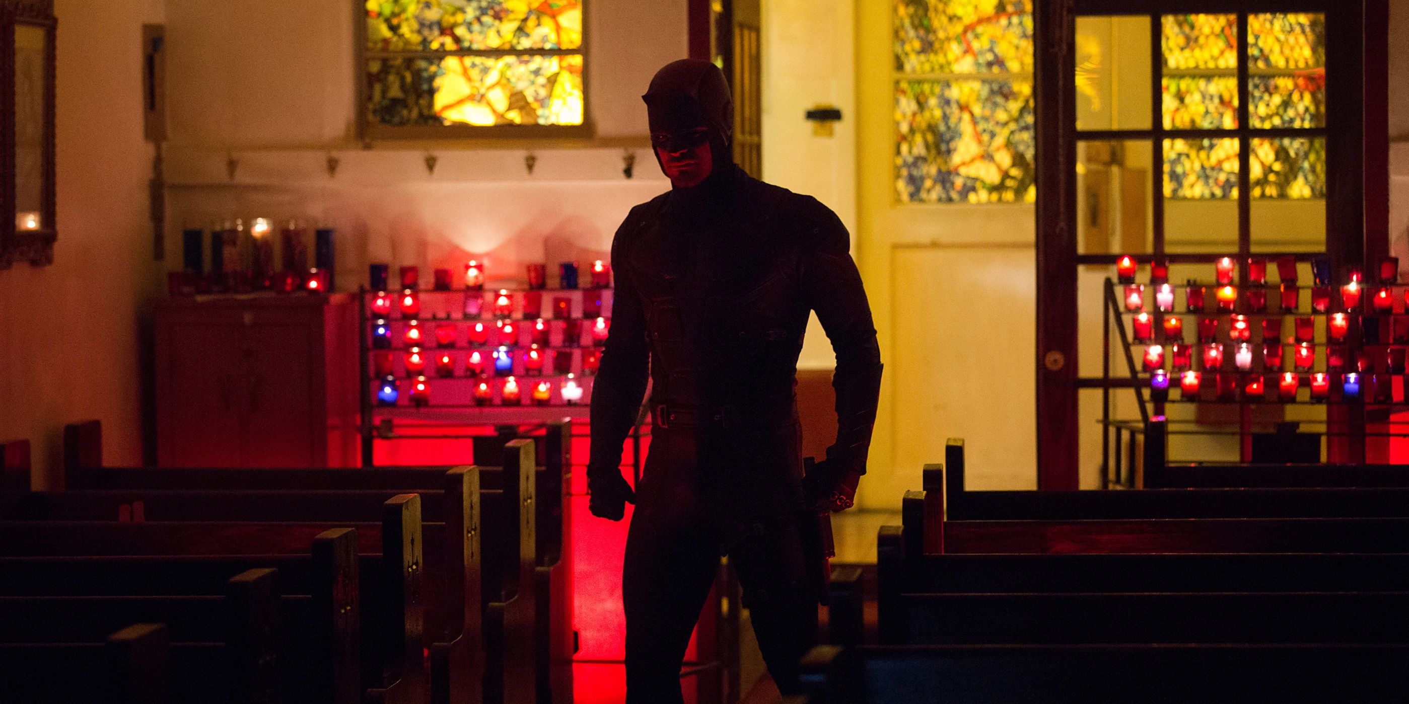 Daredevil standing in a church with a red light behind him