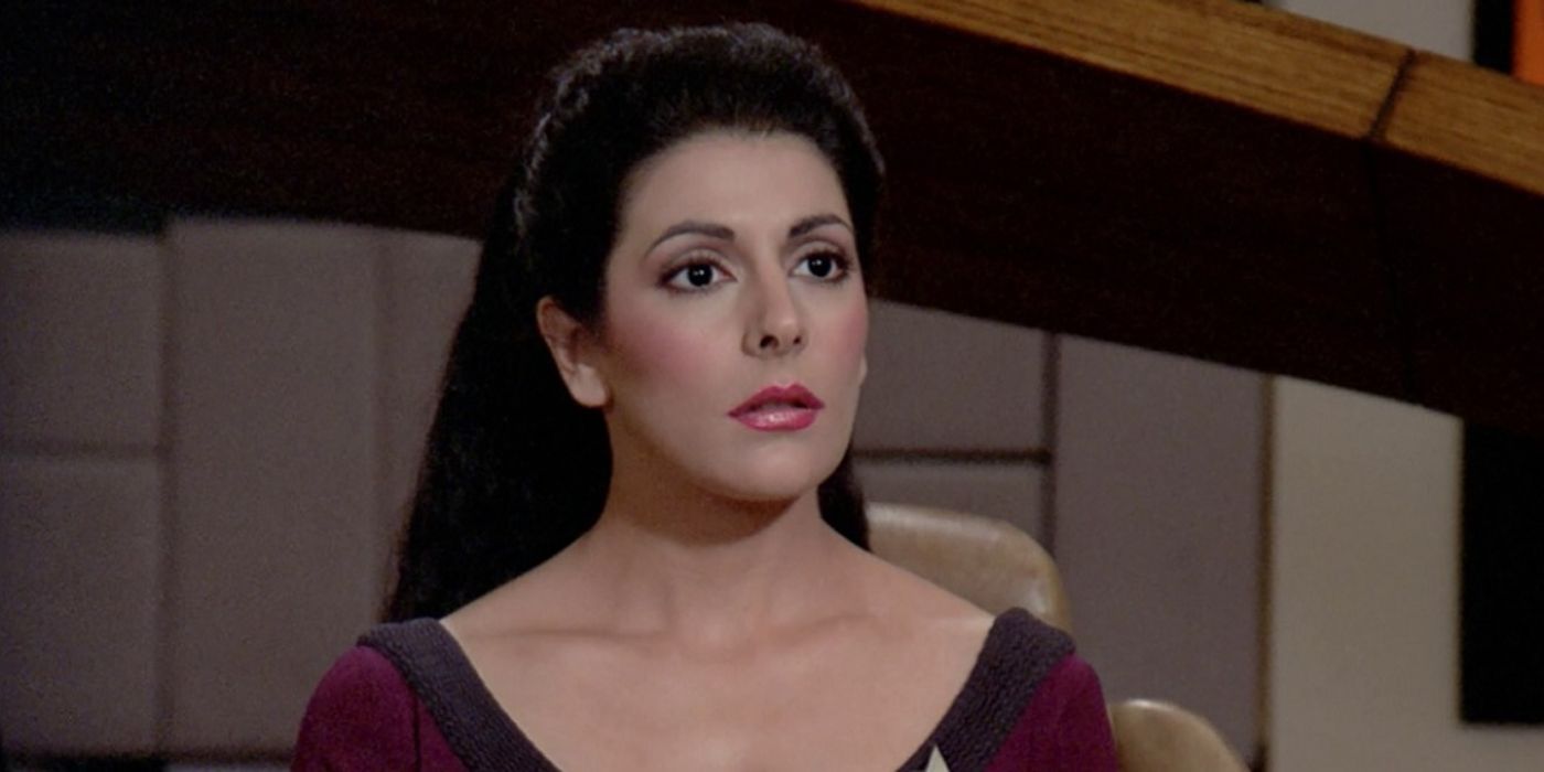 Marina Sirtis as Deanna Troi sitting on the bridge looking somber in Star Trek: The Next Generation.