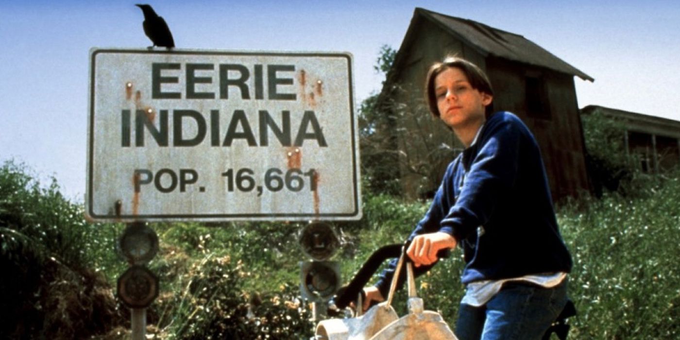 A young boy on a bike beside a sign that reads Eerie, Indiana