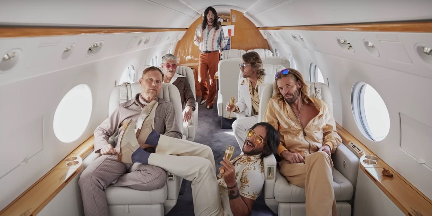 Foo Fighters wearing disco duds, holding champagne while lounging in a private jet as the Dee Gees