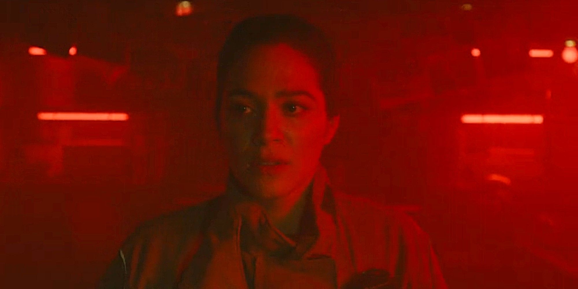 Gabriela Perez tinted in red, standing in a darkroom and looking upset in Fire Country Season 3.