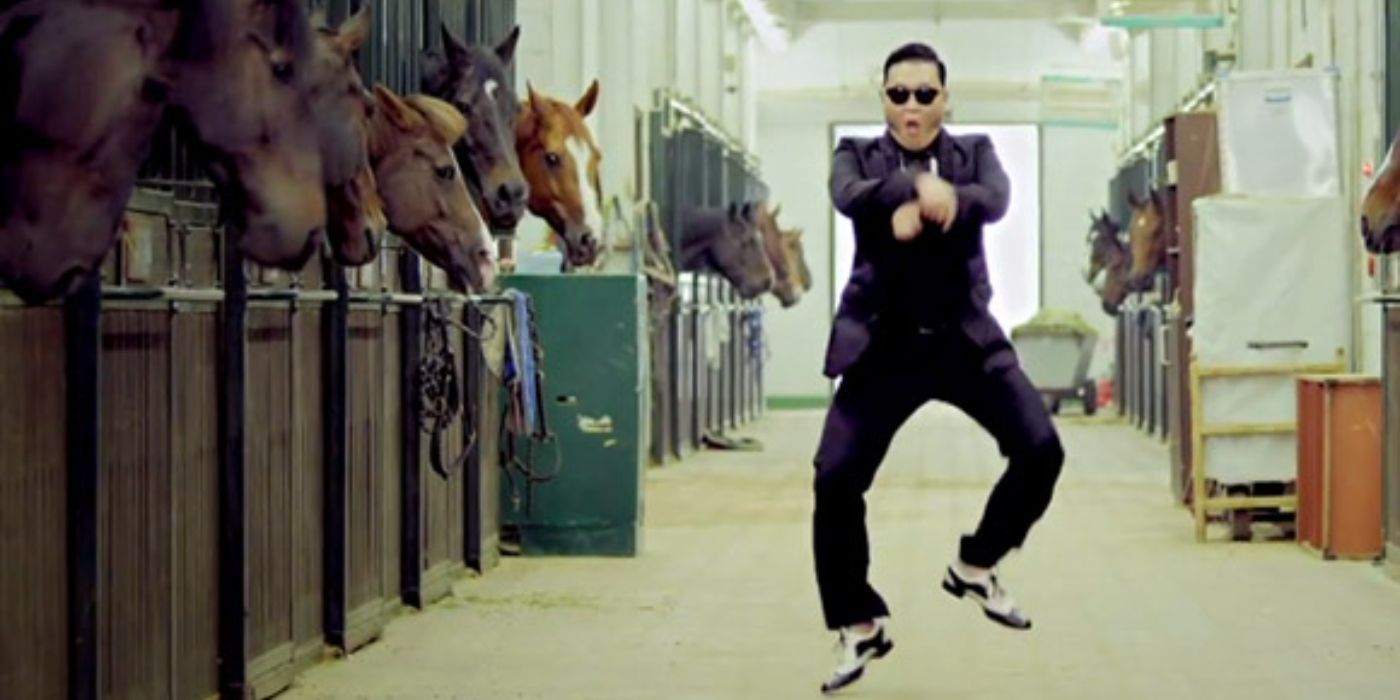 Psy doing a dance next to a stable of horses in the Gangnam Style music video