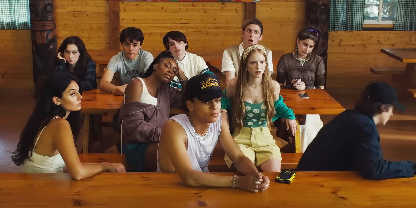 The cast of Hell of a Summer sitting at a table in a cabin