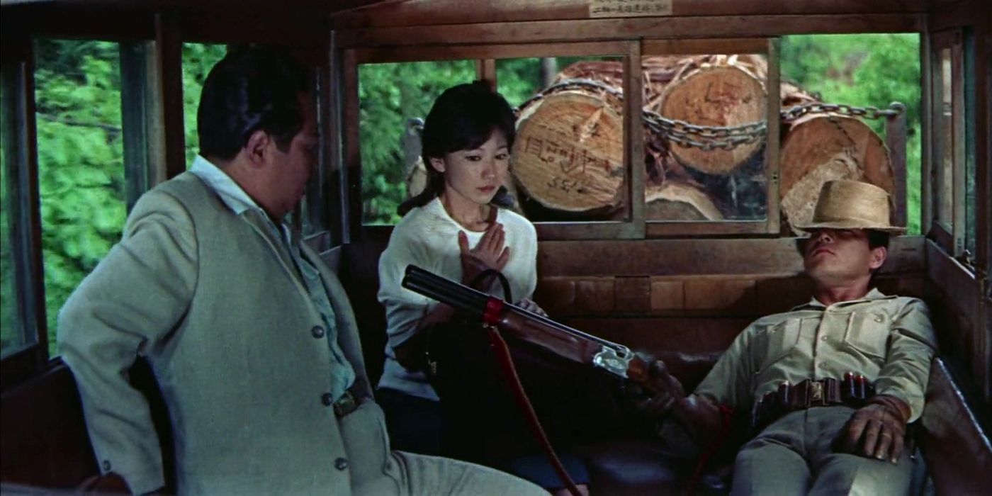 Hideaki Nitani pointing a shotgun at a man and a woman in a carriage in Man With a Shotgun