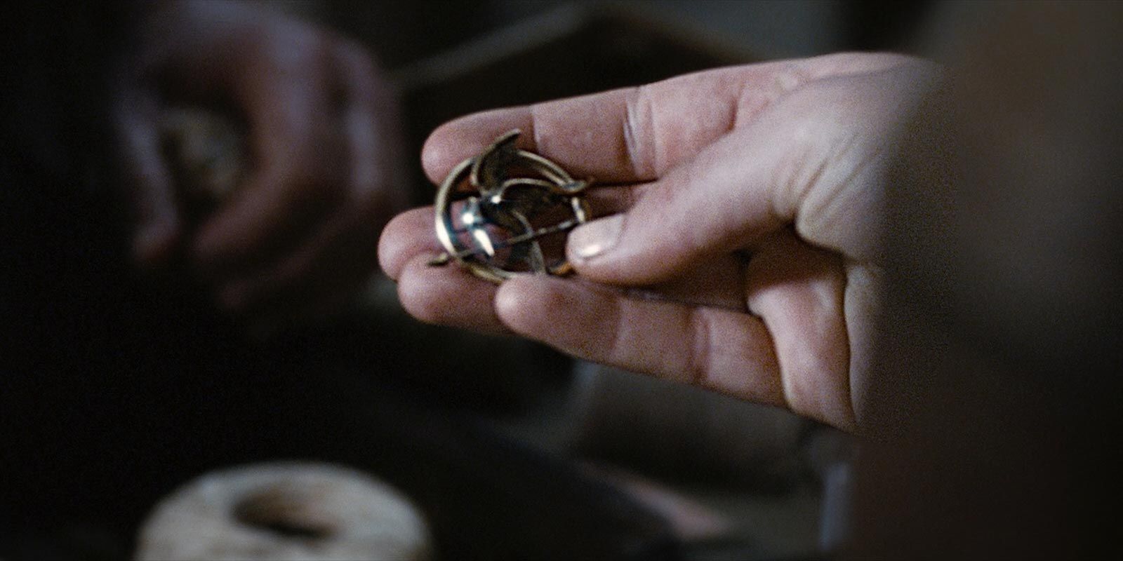Katniss (Jennifer Lawrence) finds the Mockingjay pin in The Hunger Games
