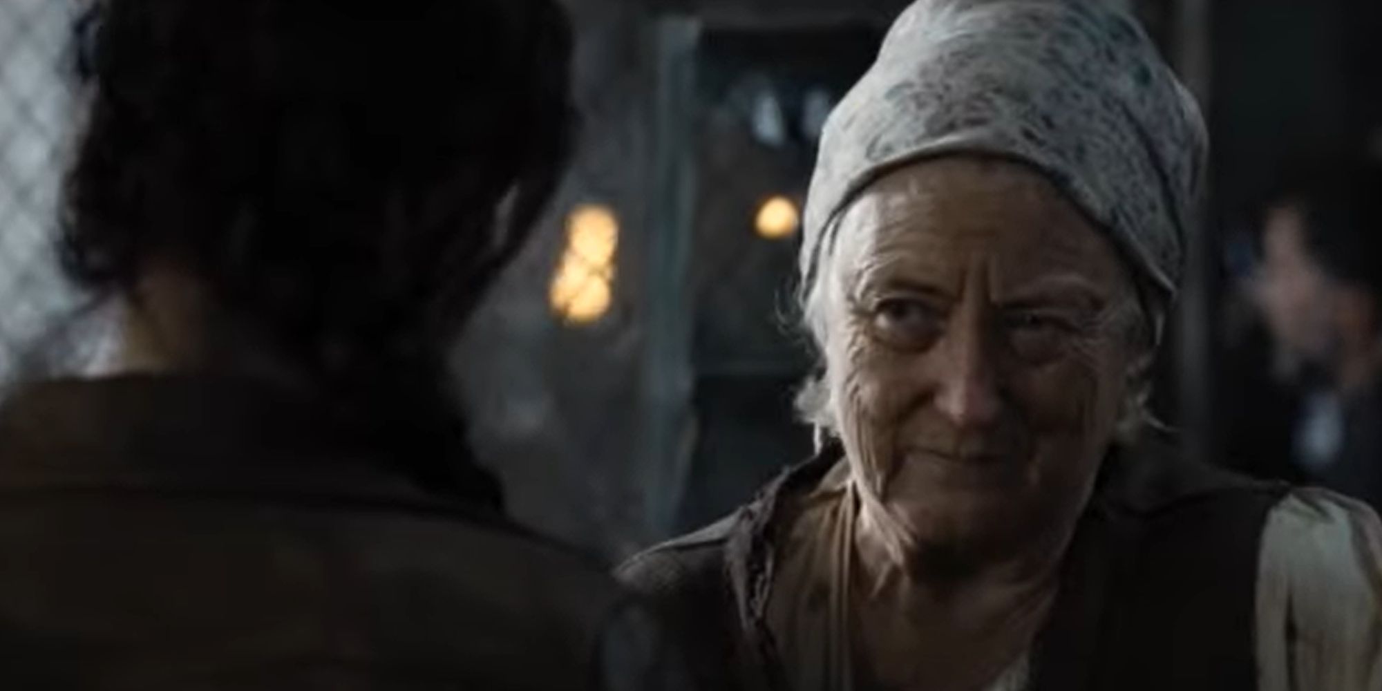 Greasy Sae (Sandra Ellis Lafferty) gives Katniss (Jennifer Lawrence) the Mockingjay pin in The Hunger Games
