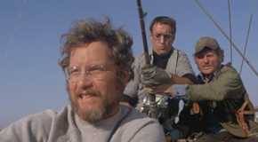 Richard Dreyfuss as Matt Hooper, with Roy Scheider and Robert Shaw as Martin Brody and Quint, holding a fishing rod behind him, in Jaws.