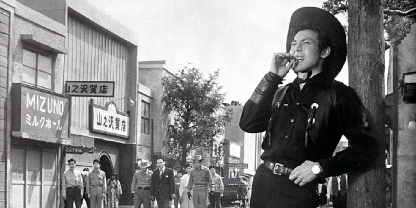 Joe Shishido as Joe the Ace leaning on a pole and grinning with a cigar in his mouth in Quick Draw Joe