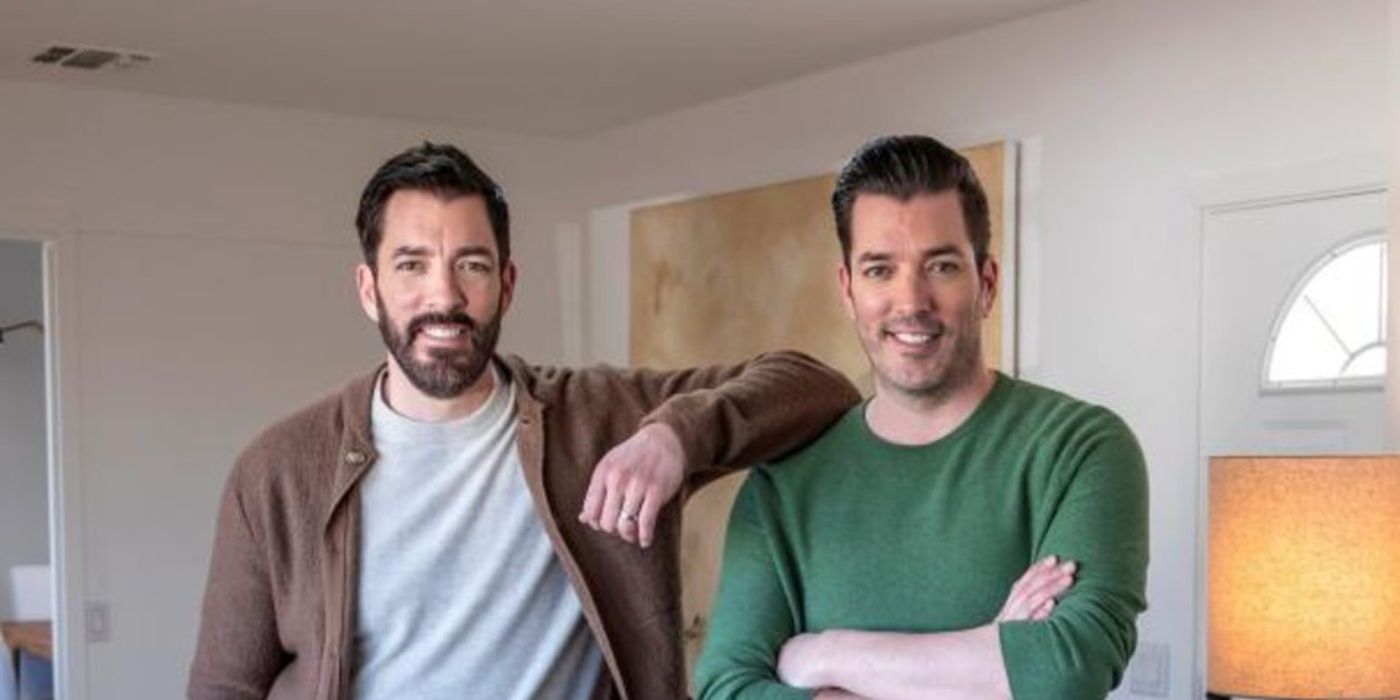 Jonathan and Drew Scott from Property Brothers stand inside a house and smile at the camera.